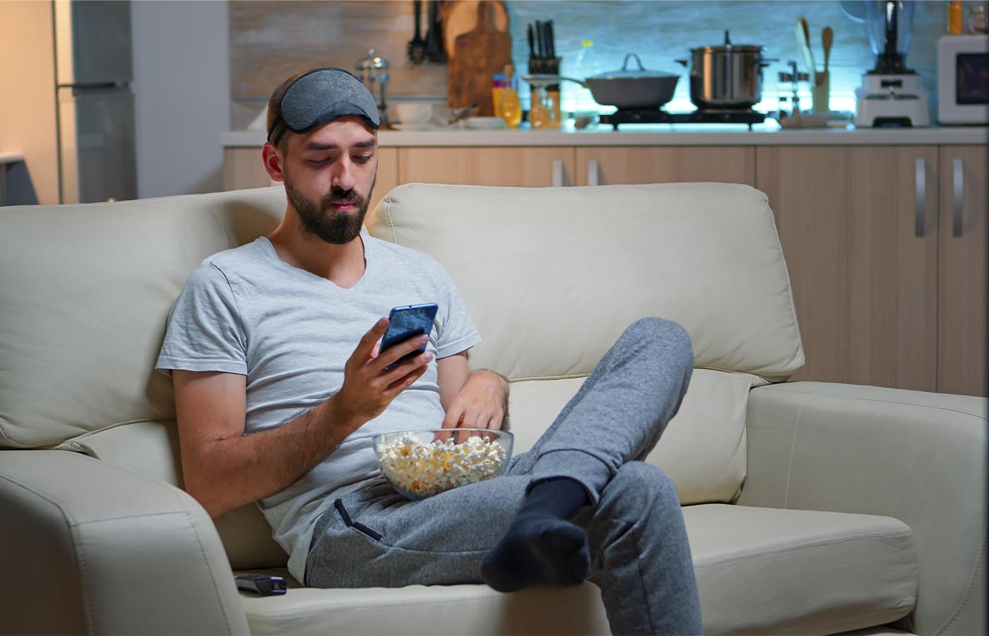 A young man sitting on the couch eating popcorn